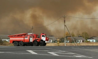Xe chữa cháy đậu cạnh ngôi làng trong khi khói bốc lên sau vụ nổ tại một kho vũ khí của Nga ngày 7/10. Ảnh: AP.