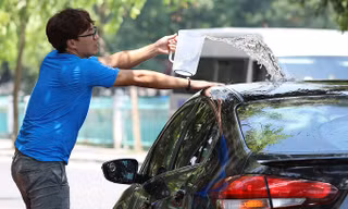 Trùm khăn kín người, dội nước 'tắm' ô tô trong nắng nóng 40 độ ở Hà Nội