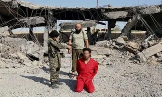 Chiến binh nhí chĩa súng vào đầu người bị ISC cáo buộc làm gián điệp.