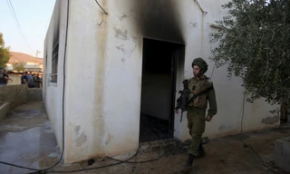 Một binh sỹ Israel đứng bên ngoài hiện trường vụ đốt phá khiến bé 18 tháng thiệt mạng