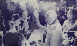 Trong ảnh, bà Diên quàng cổ chiếc khăn màu trắng