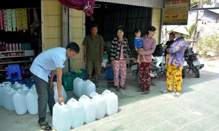 Ông Lê Thành Văn, Trưởng ấp Thanh Tùng (xã Biển Bạch, Thới Bình, Cà Mau) phát nước uống miễn phí từ nhà hảo tâm cho bà con để giải cơn khát. Ảnh: Tân Lộc