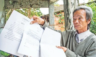 Lão nông Phạm Tấn Lực với xấp đơn tố cáo sai phạm cao tốc Đà Nẵng - Quảng Ngãi viết bằng 2 thứ tiếng Việt Trung. Ảnh: Lê Văn Chương