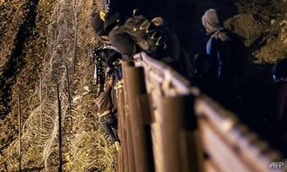 Một em bé từ Trung Mỹ đang vượt qua hàng rào ở biên giới Mỹ - Mexico để vào Mỹ hôm 1/1/2019/ (Ảnh: Guillermo Arias)