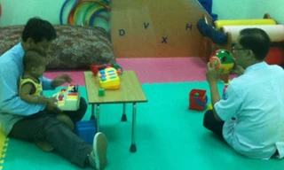 Bé Nguyễn Quốc Huy đang được ông Giao tập vật lý trị liệu với chân giả. Ảnh: Quốc Ngọc.