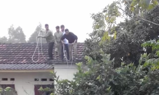 Người dân phải đứng trên nóc nhà, quăng dây xuống nhằm giăng bẫy bắt "trâu điên". Ảnh cắt từ clip do nhân chứng cung cấp.