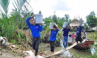 Các sinh viên tình nguyện khuân cát, đá từ dưới ghe lên bờ làm đường Ảnh: Hòa Hội