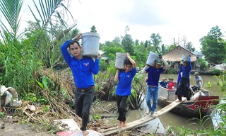 Các sinh viên tình nguyện khuân cát, đá từ dưới ghe lên bờ làm đường Ảnh: Hòa Hội