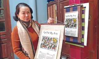 Nghệ nhân Nguyễn Thị Oanh giới thiệu cuốn lịch năm Canh Tý, với bức tranh “Đám cưới chuột” Ảnh: KIẾN NGHĨA 