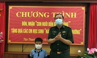 Chính ủy Bộ Chỉ huy Biên phòng Lạng Sơn Trịnh Hữu Tăng (bìa phải) tặng quà cho em Thiên Ân nhân dịp em được Đồn Biên phòng Tân Thanh (huyện Văn Lãng) nhận làm con nuôi -Ảnh: Duy Chiến 