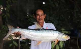 Nhà nghiên cứu Chhut Chheana và con cá chép hồi mới bắt được ở sông Mekong. (Ảnh: AP)