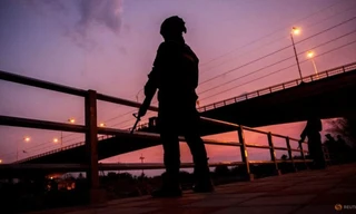 Binh lính đứng gác khi hàng trăm người băng qua sông giữa Myanmar và Thái Lan ở Mae Sot ngày 13/4. (Ảnh: Reuters)