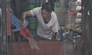 Người dân chặn cửa tát nước ngập vào nhà sau bão Wipha