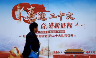 Một người dân đi qua tấm áp phích về Đại hội XX Đảng Cộng sản Trung Quốc ở Bắc Kinh ngày 14/10. (Ảnh: Reuters)