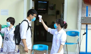Tình nguyện viên đo thân nhiệt cho thí sinh tại kì thi tốt nghiệp THPT 2020