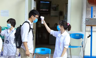 Tình nguyện viên đo thân nhiệt cho thí sinh tại kì thi tốt nghiệp THPT 2020