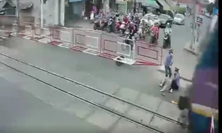 Cụ bà được 2 nữ gác chắn kéo ra khỏi đường sắt ngay trước mũi tàu. Ảnh cắt từ clip.