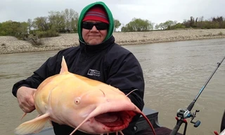 Chủ tàu câu du lịch và con cá trê bạch tạng dài hơn một mét. Ảnh: UPI.