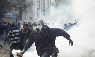 Một người biểu tình ném trả lựu đạn cay về phía cảnh sát. Ảnh: AP