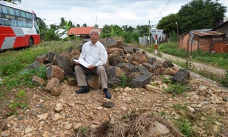 Thầy Sỹ ngồi trên đống đá do ông Đông đổ trên phần đất lấn chiếm 