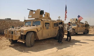 Chiến binh SDF đứng cạnh xe quân sự của Mỹ ở ngoại ô thị trấn Manbij, Aleppo, Syria, hồi tháng 3. Ảnh: AP