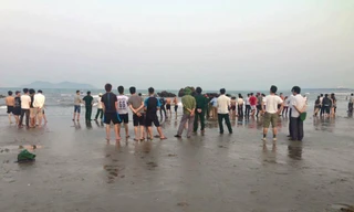 Người dân tập trung nơi bãi biển xảy ra vụ hai học sinh bị sóng cuốn mất tích khi đi chụp ảnh kỷ yếu.