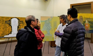 Họa sĩ Phan Ngọc Minh - áo trắng - trao đổi với người xem tại triển lãm của ông tại Boston College