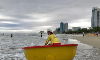 Nhân viên cứu hộ bơi thúng ra kêu gọi người tắm biển vào nơi an toàn