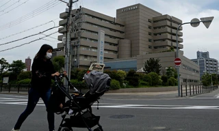 Một người phụ nữ đeo khẩu trang đẩy xe trẻ em bên ngoài Bệnh viện Juso, thành phố Osaka