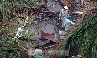 Công nhân vệ sinh môi trường đang thu gom phế thải còn lại sau vụ cháy. Ảnh: Hoàng Mạnh Thắng