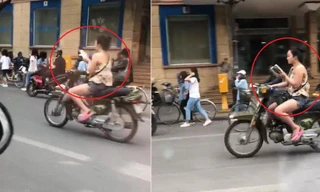 Cô gái vừa chạy xe máy vừa đọc sách trên đường phố Hà Nội