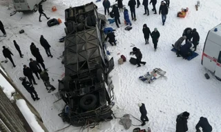 Chiếc xe buýt nằm ngửa bụng dưới sông băng. Ảnh: Twitter