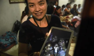 Người thân cầm ảnh các cầu thủ nhí của đội bóng Lợn Hoang. Ảnh: AFP