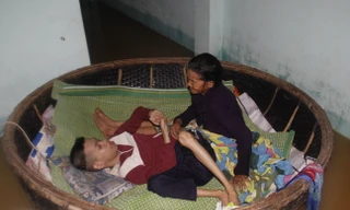 Hai mẹ con bà Đắt trong chiếc thuyền thúng nổi trôi theo nước lũ. Ảnh: Thanh Trần. 