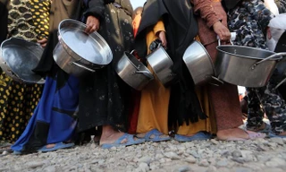 Những người dân sống tại trại tị nạn Khazir xếp hàng nhận thực phẩm cứu trợ trong tháng Ramadan. Ảnh: AFP