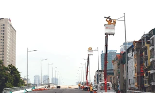 Thi công hệ thống chiếu sáng trên cầu vượt Nguyễn Văn Huyên - Hà Nội Ảnh: NHƯ Ý 