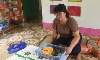 Cô giáo Hoàng Thị Nự bên cạnh kỷ vật của những học sinh đã qua đời trong vụ sạt lở tại thôn Làng Nủ