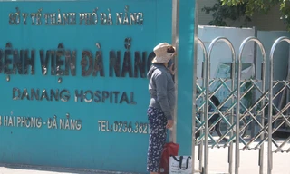 Một người nhà bệnh nhân đứng trước cổng bệnh viện sau khi bệnh viện này được cách ly y tế. Ảnh: Nguyễn Thành