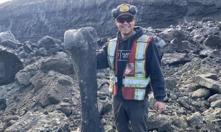 Thợ mỏ Trey Charlie chụp ảnh bên khúc xương voi ma mút tiền sử khổng lồ được anh tìm thấy ở mỏ Little Flake gần thành phố Dawson, Canada.