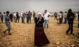 Một người phụ nữ Kurd ở Syria ôm mặt trong cơn bão bụi trên ngọn đồi nơi cô và những người khác đang chứng kiến cuộc đụng độ giữa những chiến binh thánh chiến của Nhà nước Hồi giáo (IS) và lực lượng người Kurd.