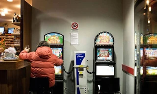 Một người đang mê mẩn bên máy đánh bạc trong quán bar.