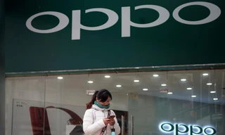 Một phụ nữ đứng trước một cửa hàng của hãng điện thoại Oppo. Ảnh: Reuters 