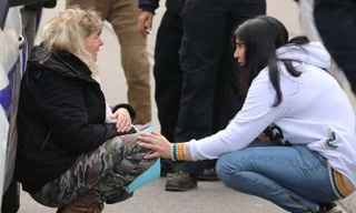 Một phụ nữ nức nở bên xe cảnh sát tại hiện trường vụ tấn công. Ảnh: CNN