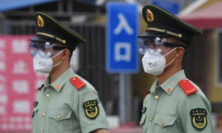 Cảnh sát bán quân sự đeo khẩu trang, kính bảo hộ khi đứng gác tại cổng chợ đầu mối Tân Phát Địa ở Bắc Kinh hôm 13/6. Ảnh: Getty Images 