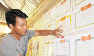 Cậu học trò Pakoh Hồ Văn Sợi bên những tấm giấy khen Ảnh: Q.M