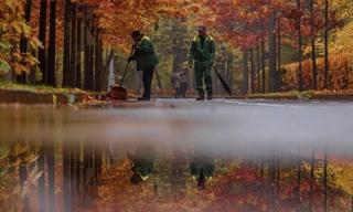 Hai công nhân môi trường quét lá trong Công viên Mátxcơva ngày 23/10. (Ảnh: Reuters)