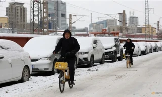 Tuyết phủ trắng những chiếc xe đậu dọc một con đường ở thủ đô Bắc Kinh, Trung Quốc, ngày 15/12. (Ảnh: Reuters)