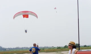 Phi công Nguyễn Tuấn Võ đang bay với lá cờ Tổ quốc. Dưới đất, anh Julien đang hướng dẫn phi công thông qua bộ đàm