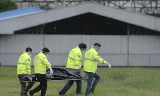 Thi thể hai người đi lậu máy bay được đưa ra khỏi đường băng. Ảnh: AP