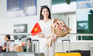 Hoa khôi Huỳnh Thúy Vi cầm hoa và cờ Việt Nam trước giờ lên máy bay.